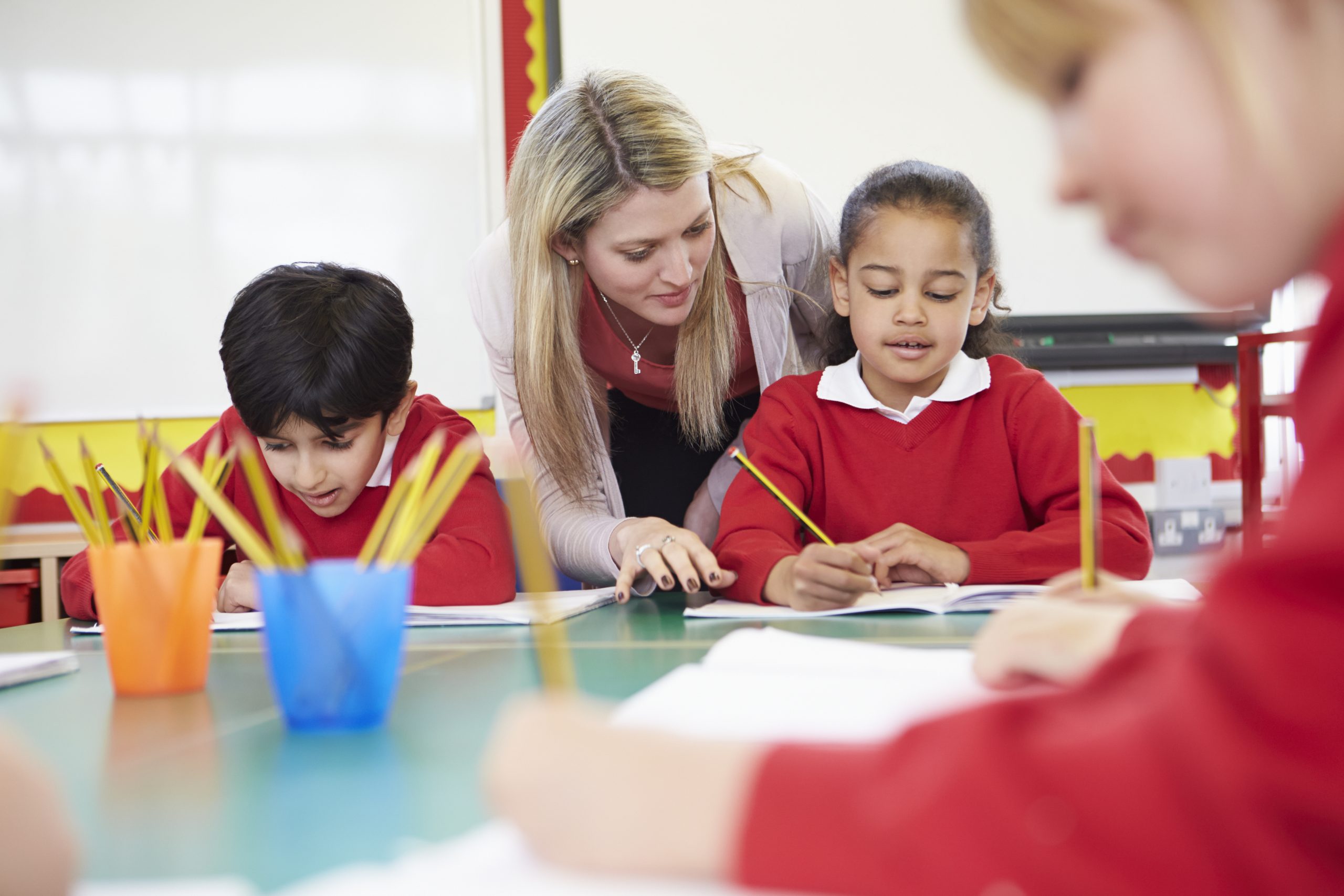 teacher-helping-female-pupil-with-writing-otrack-pupil-tracking-software